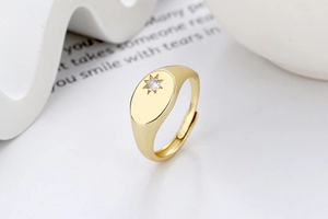 Macro detail of gold signet ring featuring an oval face with an eight-point star set zircon