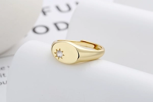 Detail of gold oval signet ring featuring starburst engraving and sparkling center stone