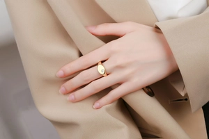 Detail of an 18K gold plated oval signet ring with a starburst set diamond on a model hand