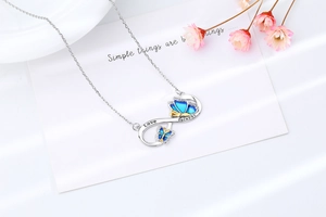 Macro shot of silver infinity necklace with blue butterfly pendant and Love Forever engraving
