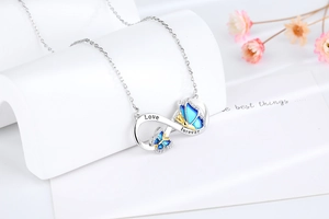 Macro view of infinity butterfly pendant with blue enamel and engraved Love Forever