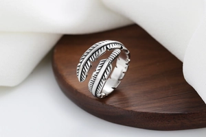 Close-up of vintage feather open ring with detailed carvings on a wooden base