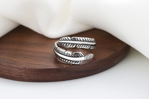 Detailed view of vintage silver feather ring with intricate texture on wooden surface