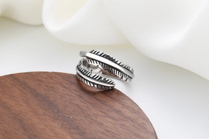 Macro view of vintage silver feather ring with oxidized textures on a wooden base