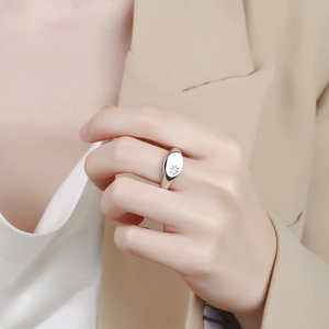 Silver signet ring with engraved starburst and diamond shown on a model hand