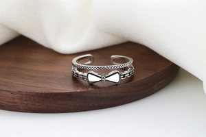 Détail de la bague double couche avec nœud et textures perlées sur support en bois