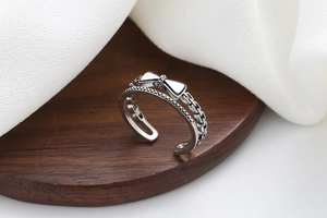 Détail d'une bague nœud en argent vintage avec texture chaîne sur support bois