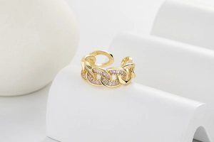 Detailed view of a gold chain link ring with sparkling white zircon inlays and open back