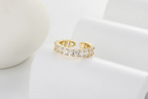 Macro view of gold open ring with marquise-cut white zircons on a marble stand