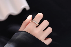 Close-up of gold geometric ring with oval zircons worn on index finger with black cuff