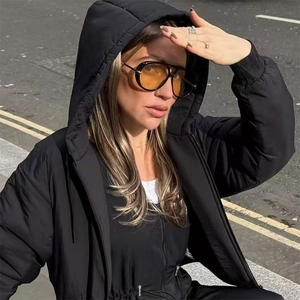 Detail of yellow lens aviator sunglasses styled with a black drawstring hooded jacket