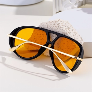 Detail of aviator sunglasses with black frame, gold temples and yellow tinted lenses
