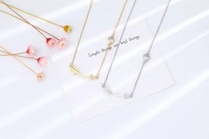 Detail view of gold and silver arrow necklaces with heart-shaped cubic zirconia charms