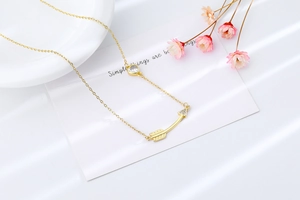 Macro shot of gold arrow necklace with heart gem on elegant white porcelain surface