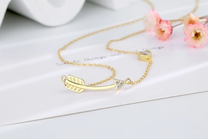 Macro detail of gold arrow necklace with heart pendant and sparkling zircon stones