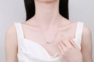 Close-up of a silver arrow necklace with zirconia stones on a model's collarbone