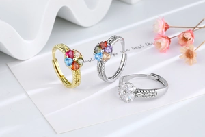 Detailed view of heart-shaped clover rings with colorful zircons on a white display