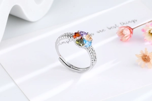 Macro detail of silver ring with colorful heart-shaped stones and woven hollow band
