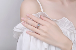 Close-up of a silver ring with colorful heart-shaped gems and vintage engraved texture