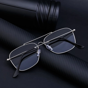Close-up of silver metal double-bridge sunglasses featuring square frames on a textured stand