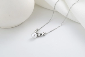Macro detail of elegant pearl pendant with polished silver beads on a minimalist necklace