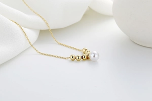 Detailed close-up of a pearl necklace with symmetrical gold beads on a silk background
