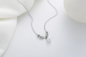 Detailed macro view of minimalist silver necklace featuring elegant pearl pendant and fine chain