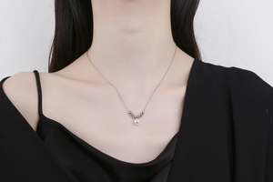 Elegant silver thin chain necklace with white pearl pendant worn on a black outfit