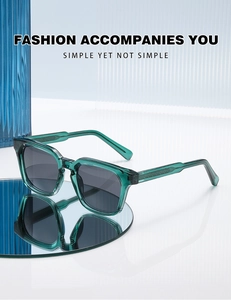 Detail of dark green transparent square sunglasses with textured temples on a mirror surface