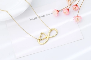 Detailed view of a gold infinity heart pendant necklace on a clean white display card