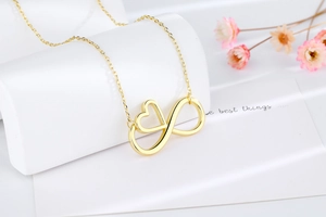 Close-up of a gold infinity heart pendant necklace on a polished minimalist display