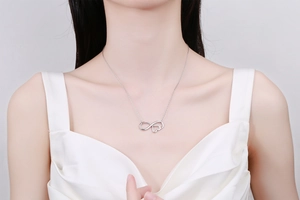 Close-up of infinity heart pendant necklace worn on neck with silver finish