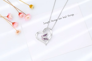 Détail du collier cœur en argent avec pendentif papillon rose et violet sur carte blanche