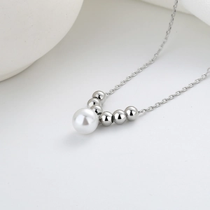 Minimalist silver necklace with white pearl and V-shaped metallic beads on white background