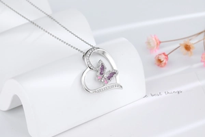 Détail du pendentif cœur papillon avec émail rose et cristaux sur une chaîne argentée