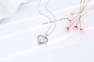 Macro view of heart pendant featuring blue zircon and engraved romantic quote on fine chain
