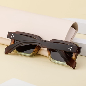 Détail de lunettes de soleil carrées écaille avec rivets étoile et un étui rose pliable
