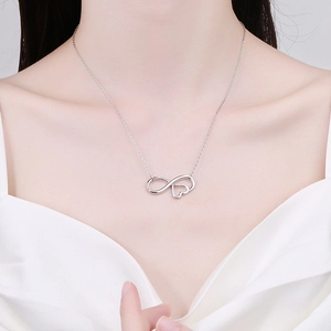 Silver infinity heart pendant necklace on female model neck with fine link chain