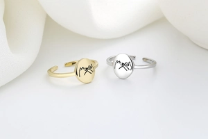 Close-up of gold and silver adjustable pinky promise rings with engraved hand gesture