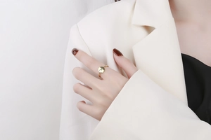 Close-up of a gold signet ring with minimalist line art on a model wearing white suit