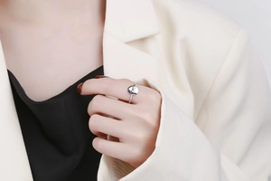 Detailed view of silver minimalist ring with engraved circular face worn by a model