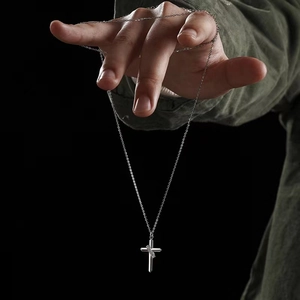 Macro detail of silver cross pendant with textured wrap on elegant O-chain link