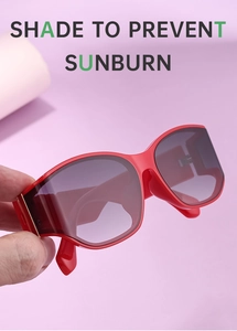 Close-up of red oversized sunglasses with glossy wide frames and dark gradient lenses