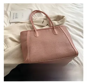 Détail d'un cabas rose montrant la texture du tissu et les garnitures en cuir fin