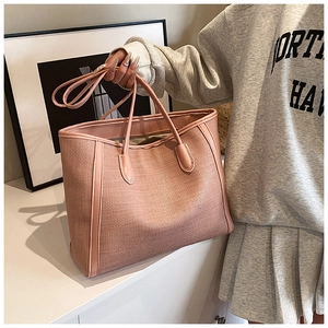 Gros plan d'un sac cabas rose avec texture tissée et finitions en cuir lisse
