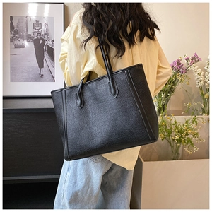 Vue arrière d'un mannequin portant un grand sac cabas noir à texture tissée à l'épaule chic