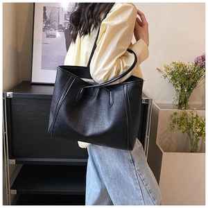 Détail d'un grand sac cabas noir avec texture tressée et longues anses d'épaule