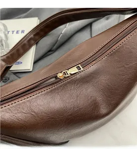 Close-up of smooth gold metal zipper on brown pebble leather hobo shoulder bag