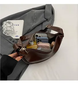 Interior storage view of brown leather crescent bag holding phone, wallet and cosmetics
