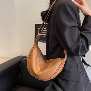 Detailed view of caramel crescent shoulder bag with pleated texture on a model